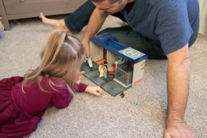 Father and daughter playing with Playmobil Take Along Police Station