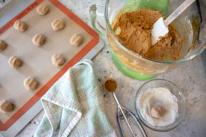 molasses cookie dough in the mixing bowl and cookies on a baking sheet ready for the oven