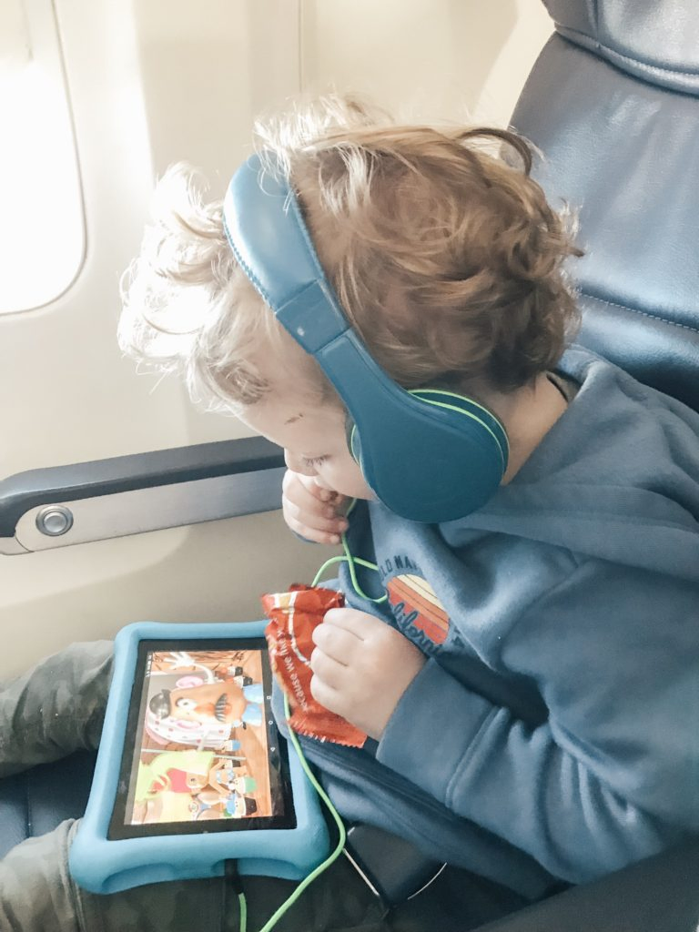 child on airplane watching a movie on his tablet