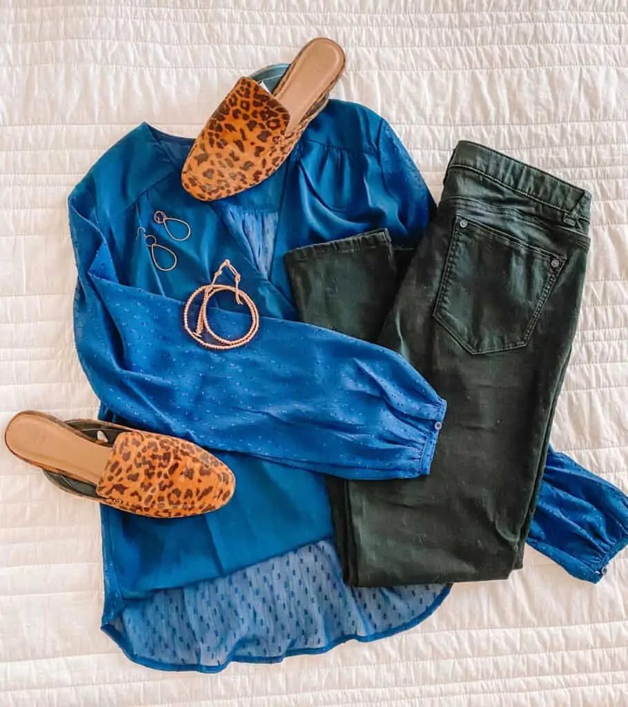 Flat lay of blue top, black jeans, leopard shoes