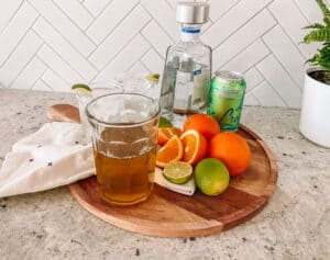 Orange simple syrup on a tray with all the fixings for a tequila soda