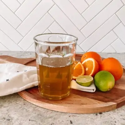 Orange simple syrup on a tray with citrus fruit