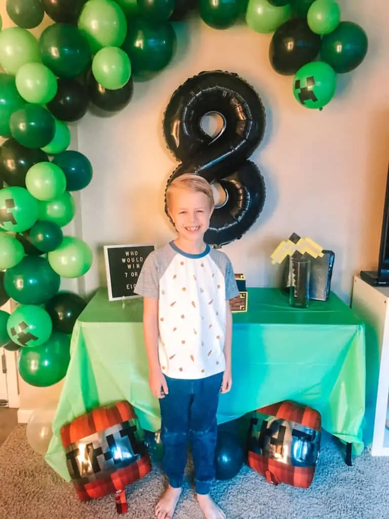 kid standing in front of balloon arch